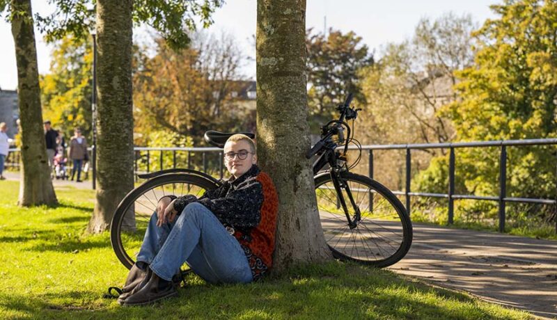 cyclist taking a rest by a tree in a Galway park